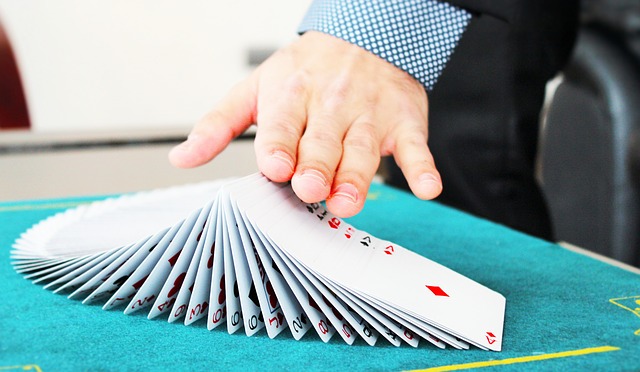 A hand ruffles a deck of cards spread on a table