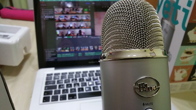 A microphone is shown close up with a computer in the background