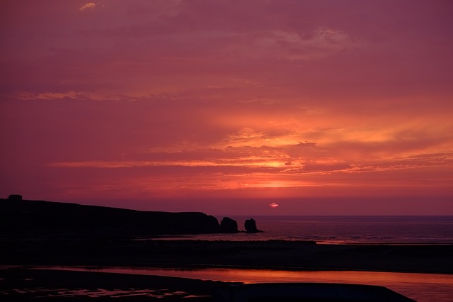 The sun sets over water creating a pink and purple sky